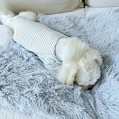 A dog is sitting on a gray, fluffy pet blanket draped over its back.